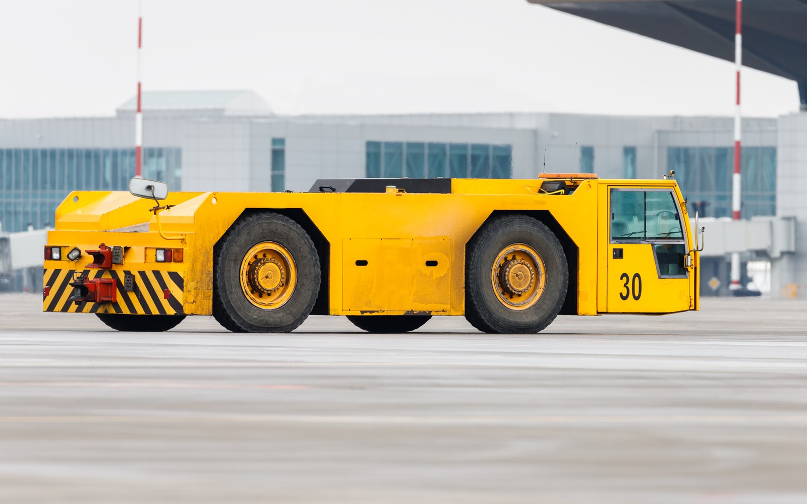 Ein gelber Flugzeugschlepper mit der Nummer 30 auf einem Flughafenvorfeld.